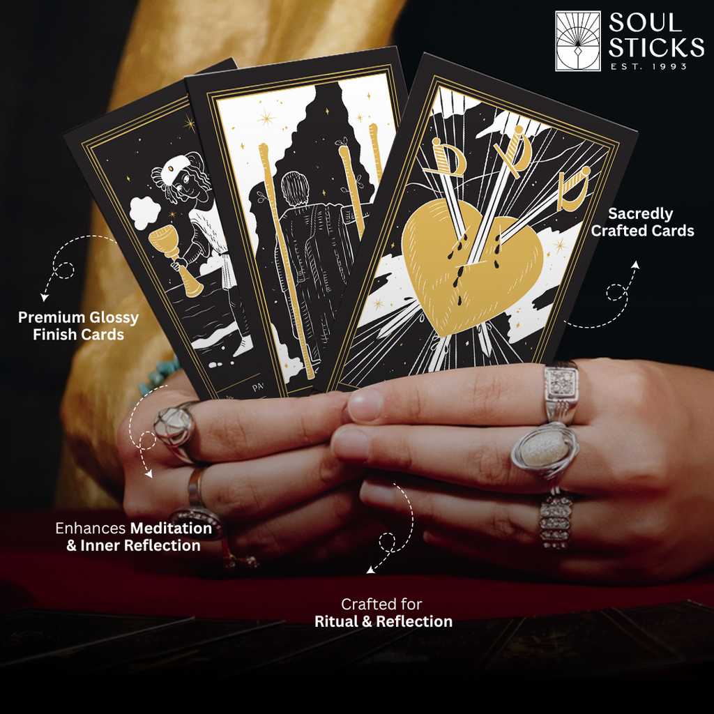 Cards held in hands: “Hands holding three glossy Shadows of Light tarot cards in black, white and gold, including the Three of Swords.”