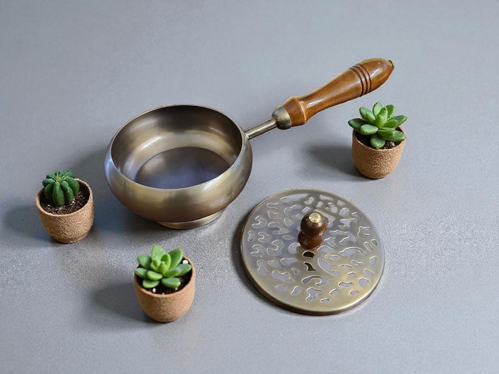 Crystal Fairy Patch bronze finish metal charcoal burner with wooden handle and decorative lid, surrounded by small succulents.