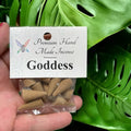 Crystal Fairy Patch Goddess premium hand-made cone incense in a clear plastic bag held against a green monstera leaf background.