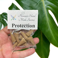 Crystal Fairy Patch Protection premium hand-made cone incense in a clear plastic bag held against a green monstera leaf.