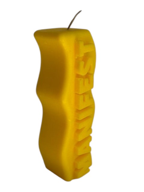 Crystal Fairy Patch yellow sculptural candle with a wavy silhouette and raised MANIFEST lettering for meditation and decor.