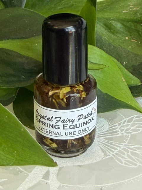 Crystal Fairy Patch Spring Equinox Ostara ritual oil in a small glass bottle with botanical herbs, set against green leaves.
