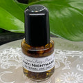 Small bottle labeled 'Anti Nightmare' with a black cap on a decorative surface with green leaves in the background.