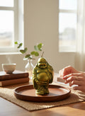 Crystal Fairy Patch handcrafted green Buddha candle with gold dusting on a wooden tray, held by hands preparing to light it.