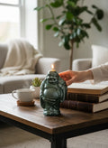 Crystal Fairy Patch handcrafted Buddha candle with a shimmering green pearl finish, lit on a wooden table with books.
