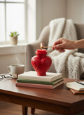 Crystal Fairy Patch red heart-shaped apothecary bottle candle with floral embossing being lit on a stack of books.