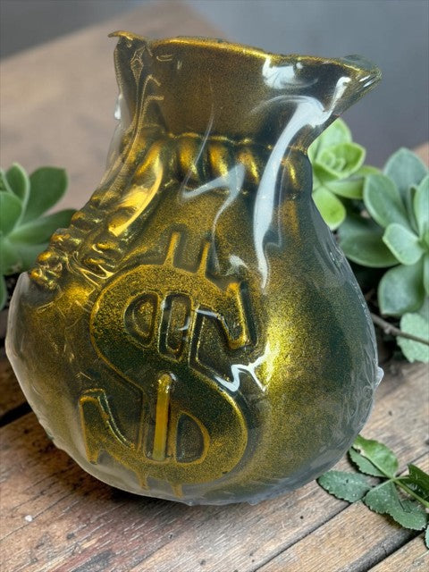 Crystal Fairy Patch handcrafted money bag candle with a metallic gold dollar sign finish on a rustic wooden surface.