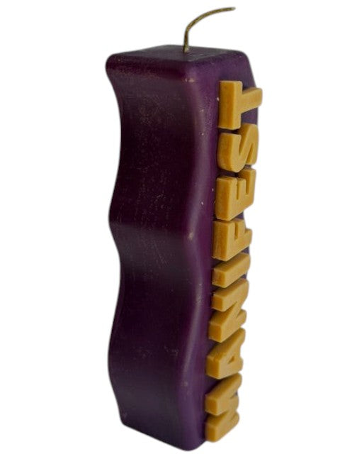 Crystal Fairy Patch purple handcrafted pillar candle with raised yellow MANIFEST lettering and wavy side design.