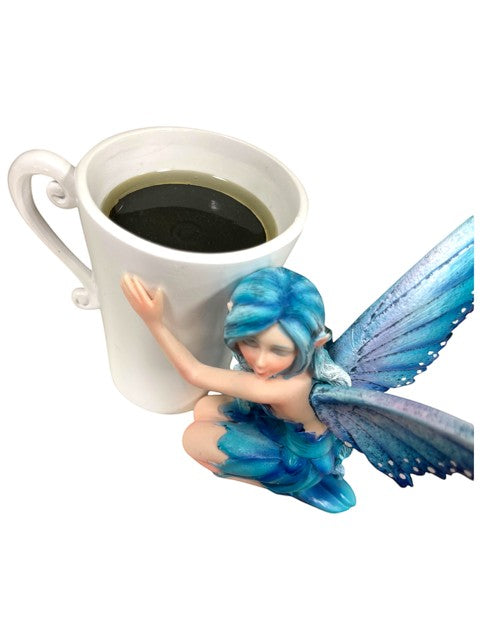 My Store Amy Brown Coffee Comfort Relaxing Faery Cup with blue wings and blue outfit, holding a white mug filled with dark liquid.