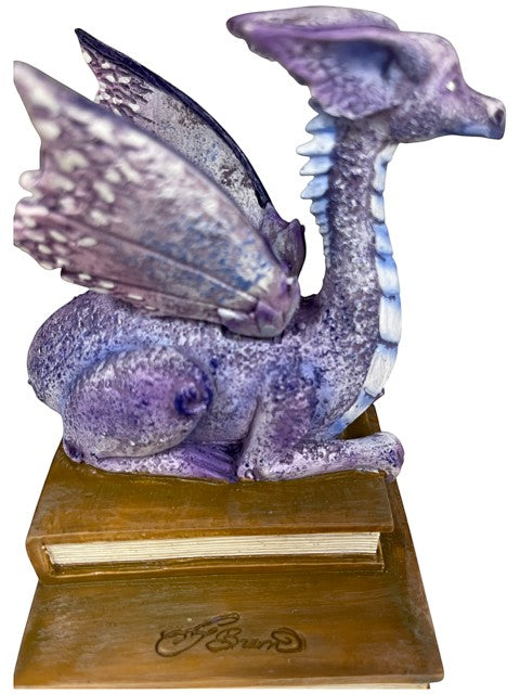 My Store lavender, purple, and blue dragon figurine perched on a stack of antique books. Detailed wings and serene expression.