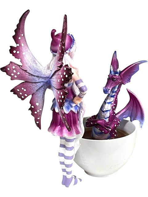 My Store fairy figurine with purple butterfly wings and striped stockings next to a purple dragon in a white teacup.