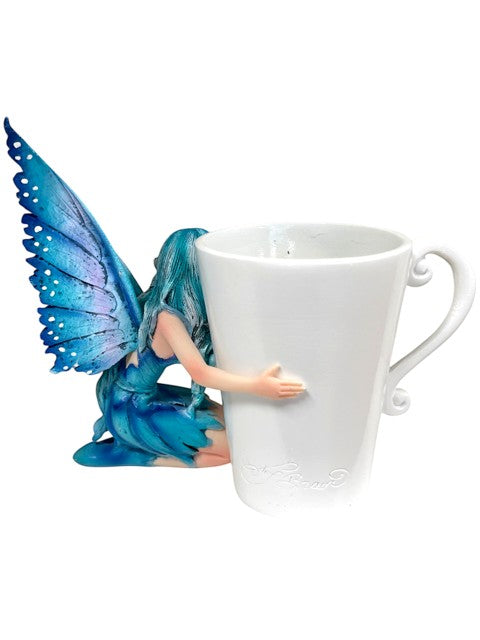 My Store white ceramic mug with a blue-winged fairy figure hugging it. Features intricate wing detail.