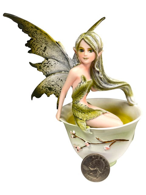 My Store Green Tea Fairy figurine by Amy Brown Art, sitting in a teacup with green liquid. Features delicate wings and leaf-like attire.