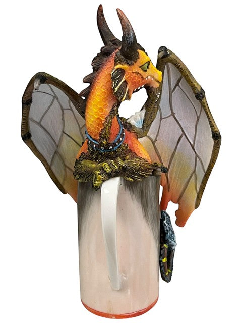 My Store's "Mead Dragon" figurine by Stanley Morrison, a fantasy collectible with orange and yellow scales, translucent wings, and a blue studded collar, perched on a mug.