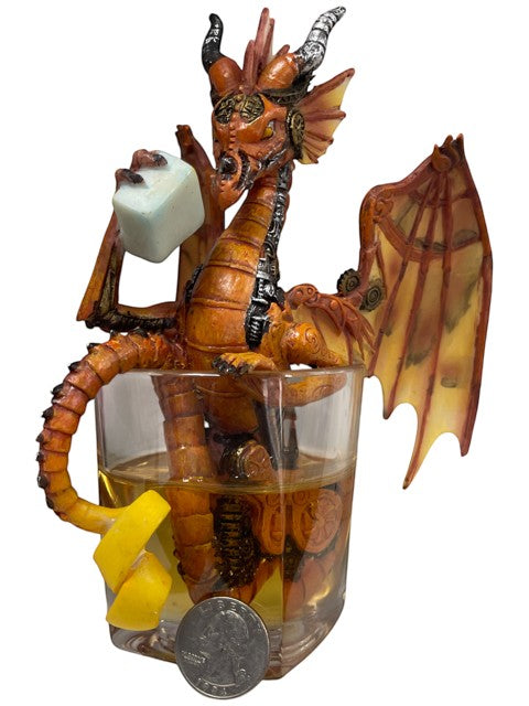 My Store Steampunk dragon figurine in orange and bronze, holding a light blue cube, sitting in a glass of amber liquid with lemon peel.