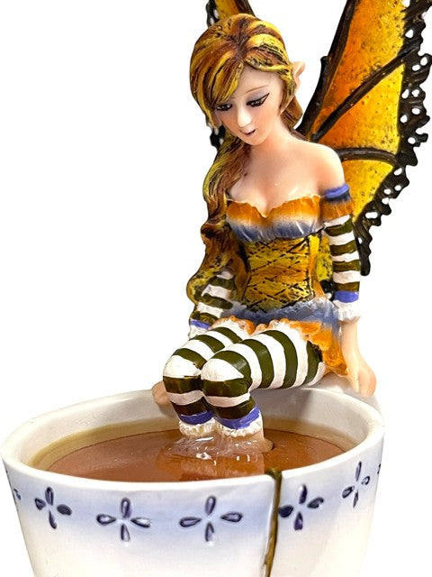 My Store Warm Toes Faery figurine by Amy Brown Art, sitting with feet in a teacup. Features orange butterfly wings, striped stockings, and detailed dress.