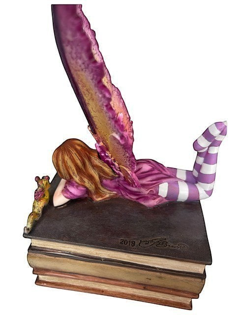 My Store Book Club Fae figurine of a fairy with purple wings lying on books, wearing a purple dress and striped socks.