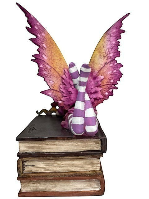 My Store Book Club Fae figurine with purple and yellow wings sitting on stack of books.