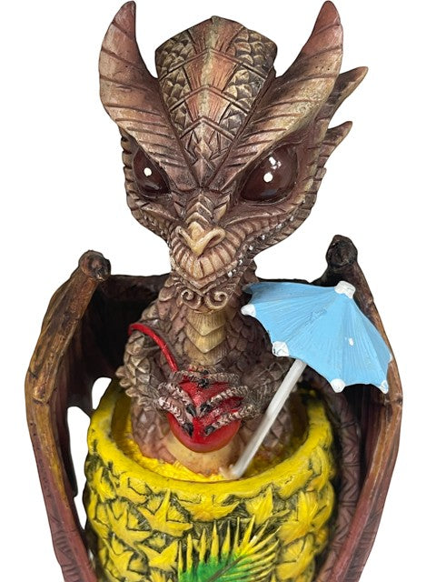 My StoreHere Drinks and Dragons Series Mai Tai Dragon figurine by Stanley Morrison. Detailed brown dragon with large eyes, holding a red cherry and a blue umbrella, seated in a pineapple.